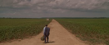 Movie still from “Walk the Line” (2005), directed by James Mangold – A man walking down a dirt road holding a briefcase; Extreme Wide shot, High angle