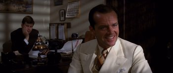 Movie still from “Chinatown” (1974), directed by Roman Polanski – A man sitting at a desk wearing a white suit and tie; Close Up shot, Low angle