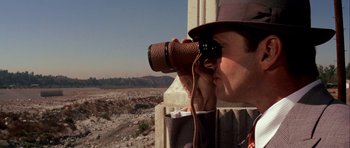 Movie still from “Chinatown” (1974), directed by Roman Polanski – A man looking through binoculars while standing on a ledge; Close Up shot, High angle