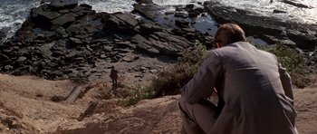 Movie still from “Chinatown” (1974), directed by Roman Polanski – A man standing on top of a hill next to a body of water; Extreme Wide shot, High angle