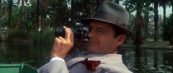 Movie still from “Chinatown” (1974), directed by Roman Polanski – A man wearing a hat taking a picture with a camera; Close Up shot, Low angle