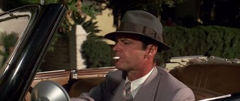 Movie still from “Chinatown” (1974), directed by Roman Polanski – A man wearing a suit and a hat is smoking a cigarette; Close Up shot, Low angle