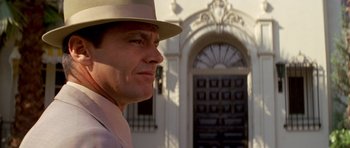 Movie still from “Chinatown” (1974), directed by Roman Polanski – A man wearing a hat standing in front of a building; Close Up shot, Low angle