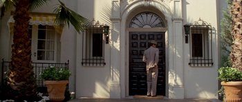 Movie still from “Chinatown” (1974), directed by Roman Polanski – A man standing in front of an open door of a building; Wide shot, Low angle