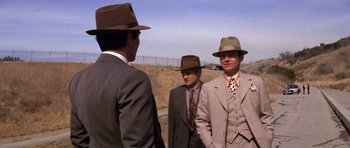 Movie still from “Chinatown” (1974), directed by Roman Polanski – A group of men standing next to each other wearing suits and hats; Medium shot, Over the shoulder angle