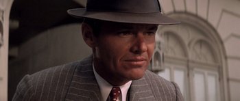Movie still from “Chinatown” (1974), directed by Roman Polanski – A person wearing a suit and a hat; Close Up shot, Over the shoulder angle