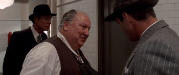 Movie still from “Chinatown” (1974), directed by Roman Polanski – A man in a vest and hat talking to another man in a hat; Close Up shot, Over the shoulder angle