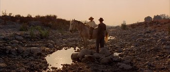 Movie still from “Chinatown” (1974), directed by Roman Polanski – Two men on a white horse near a river; Wide shot, Low angle