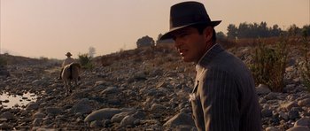 Movie still from “Chinatown” (1974), directed by Roman Polanski – A man wearing a hat standing on top of a rocky hill; Close Up shot, Over the shoulder angle