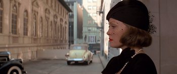 Movie still from “Chinatown” (1974), directed by Roman Polanski – A woman in a black dress and a hat is standing in the street; Close Up shot, Over the shoulder angle