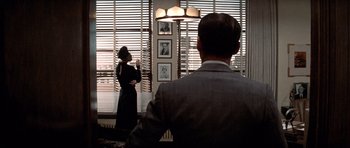 Movie still from “Chinatown” (1974), directed by Roman Polanski – A man and a woman are standing in front of a window; Medium shot, Over the shoulder angle