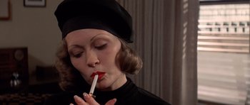 Movie still from “Chinatown” (1974), directed by Roman Polanski – A woman in a black hat is smoking a cigarette; Close Up shot, Low angle