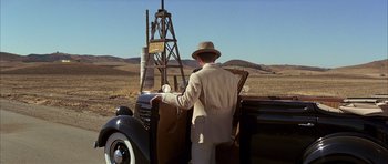 Movie still from “Chinatown” (1974), directed by Roman Polanski – A man standing next to an old car in the desert; Wide shot, Low angle