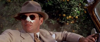 Movie still from “Chinatown” (1974), directed by Roman Polanski – A man in a suit and tie with a hat and sunglasses; Close Up shot, Low angle