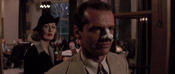 Movie still from “Chinatown” (1974), directed by Roman Polanski – A man wearing a suit and tie with a fake nose on his face; Close Up shot, Low angle