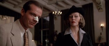 Movie still from “Chinatown” (1974), directed by Roman Polanski – A man and a woman in a room with lights in the background; Close Up shot, Low angle