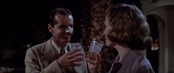 Movie still from “Chinatown” (1974), directed by Roman Polanski – A man and a woman holding glasses of whiskey; Medium shot, Over the shoulder angle