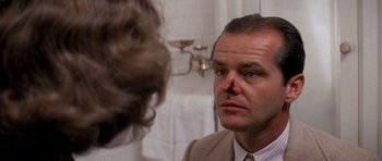 Movie still from “Chinatown” (1974), directed by Roman Polanski – A man in a suit and tie looking into a mirror; Close Up shot, Over the shoulder angle