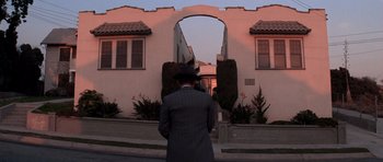 Movie still from “Chinatown” (1974), directed by Roman Polanski – A man standing in front of an archway in front of a building; Wide shot, Low angle