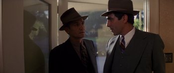 Movie still from “Chinatown” (1974), directed by Roman Polanski – Two men in suits and hats are standing next to each other; Medium shot, Over the shoulder angle
