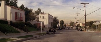 Movie still from “Chinatown” (1974), directed by Roman Polanski – An old car driving down a street next to a tall building; Extreme Wide shot, High angle