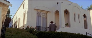Movie still from “Chinatown” (1974), directed by Roman Polanski – A man in a suit and hat standing in front of a house; Wide shot, Low angle