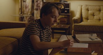 Movie still from “Wildlife” (2018), directed by Paul Dano – A young boy is writing on a piece of paper; Medium shot, High angle