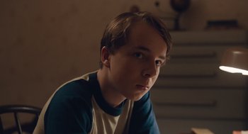 Movie still from “Wildlife” (2018), directed by Paul Dano – A young man sitting in front of a staircase; Close Up shot, Low angle