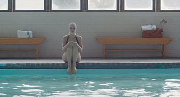Movie still from “Wildlife” (2018), directed by Paul Dano – A woman sitting on the edge of a swimming pool; Wide shot, High angle