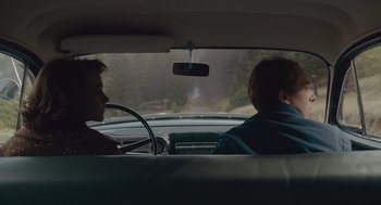 Movie still from “Wildlife” (2018), directed by Paul Dano – Two people in the back seat of a car looking out the window; Medium shot, Over the shoulder angle