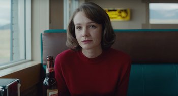 Movie still from “Wildlife” (2018), directed by Paul Dano – A woman sitting in a booth with a bottle of beer; Close Up shot, Over the shoulder angle