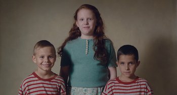 Movie still from “Wildlife” (2018), directed by Paul Dano – A girl standing between two young boys in striped shirts; Medium shot, High angle