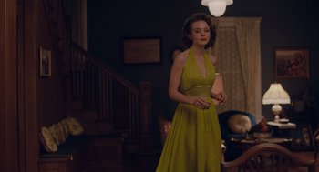 Movie still from “Wildlife” (2018), directed by Paul Dano – A woman in a yellow dress is holding a phone; Medium shot, Over the shoulder angle