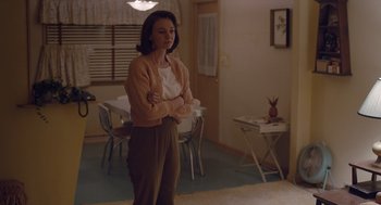 Movie still from “Wildlife” (2018), directed by Paul Dano – A woman standing in a room with her arms crossed; Medium shot, Over the shoulder angle