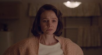 Movie still from “Wildlife” (2018), directed by Paul Dano – A young woman with short brown hair wearing a white shirt and a pink sweater; Close Up shot, Over the shoulder angle