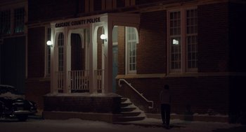 Movie still from “Wildlife” (2018), directed by Paul Dano – A person standing in front of a building at night; Extreme Wide shot, Low angle