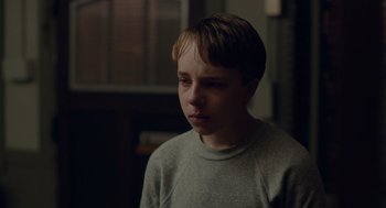 Movie still from “Wildlife” (2018), directed by Paul Dano – A young boy is looking down at the floor; Close Up shot, Over the shoulder angle