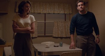 Movie still from “Wildlife” (2018), directed by Paul Dano – A man and a woman standing in front of a dining room table; Medium shot, Low angle