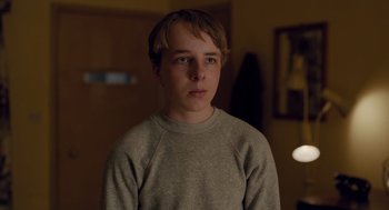 Movie still from “Wildlife” (2018), directed by Paul Dano – A young man in a gray shirt is looking at the camera; Close Up shot, Over the shoulder angle