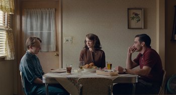 Movie still from “Wildlife” (2018), directed by Paul Dano – A group of people sitting at a table with food; Medium shot, Over the shoulder angle
