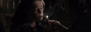 Movie still from “Women Talking” (2022), directed by Sarah Polley – A person lighting a cigarette in a dark room; Close Up shot, High angle