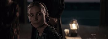 Movie still from “Women Talking” (2022), directed by Sarah Polley – A woman is looking into the camera while a man is standing behind her; Close Up shot, Over the shoulder angle