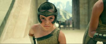 Movie still from “Wonder Woman 1984” (2020), directed by Patty Jenkins – A young girl wearing a helmet while standing in front of a group of people; Close Up shot, Low angle
