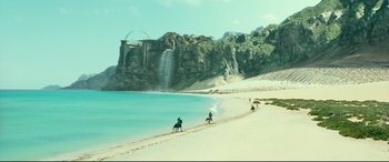Movie still from “Wonder Woman 1984” (2020), directed by Patty Jenkins – People riding horses on the beach near a waterfall; Extreme Wide shot, High angle