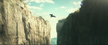 Movie still from “Wonder Woman 1984” (2020), directed by Patty Jenkins – A person jumping a horse over a cliff; Extreme Wide shot, Overhead angle