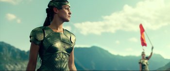 Movie still from “Wonder Woman 1984” (2020), directed by Patty Jenkins – A woman in a green costume looking at the sky; Medium shot, Low angle