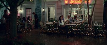 Movie still from “Wonder Woman 1984” (2020), directed by Patty Jenkins – A woman sitting at a table with a lot of candles on it; Wide shot, Over the shoulder angle