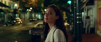 Movie still from “Wonder Woman 1984” (2020), directed by Patty Jenkins – A beautiful young woman standing on a city street at night; Close Up shot, Over the shoulder angle