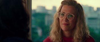 Movie still from “Wonder Woman 1984” (2020), directed by Patty Jenkins – A person wearing glasses with a city in the background; Close Up shot, Over the shoulder angle