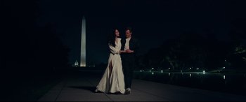 Movie still from “Wonder Woman 1984” (2020), directed by Patty Jenkins – A man and a woman holding hands while standing next to each other; Wide shot, Over the shoulder angle